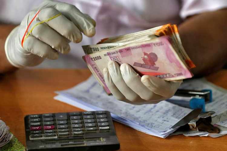 A trader wearing protective hand gloves count Indian currency notes at a market during a 21-day nationwide lockdown to limit the spreading of coronavirus disease (COVID-19) in Kochi