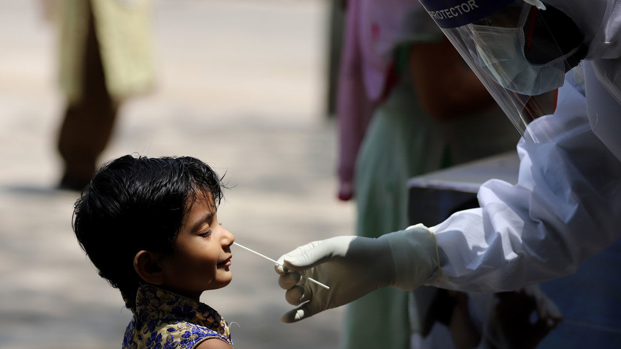 A girl reacts as a doctor takes a swab from her nose to test