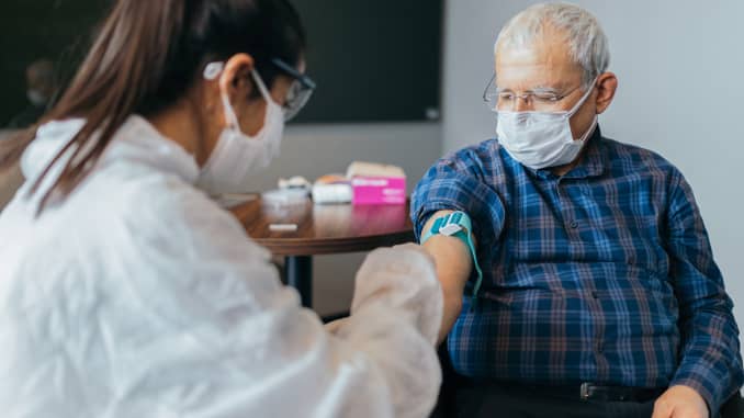 106810780-1607958402603-gettyimages-1289747714-femaledoctorwearingprotectivesuitinjectingvaccineintoseniorp