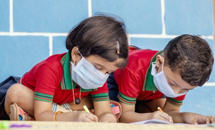 kids-busy-in-writing-with-medical-face-mask-wearing-due-to-covid19-or-picture-id1218814203-696×421