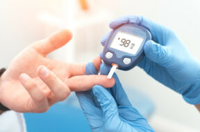 Doctor checking blood sugar level with glucometer