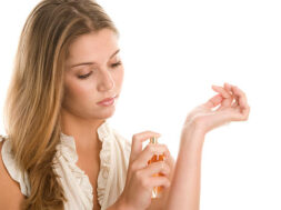 Young beautiful woman spraying perfume on hand