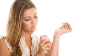 Young beautiful woman spraying perfume on hand