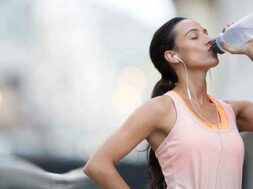 Woman drinking water after exercising on city street