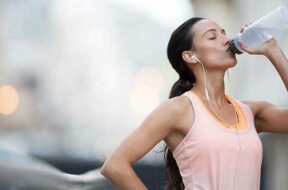 Woman drinking water after exercising on city street