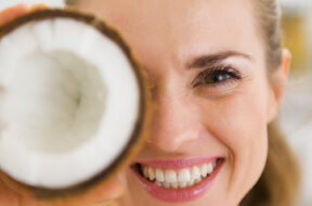 Happy,Young,Woman,Holding,Coconut,Piece,In,Front,Of,Eye