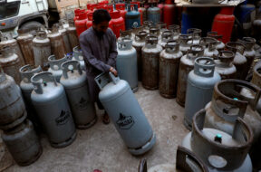 FILE PHOTO: A worker moves a liquid petroleum gas cylinder at a workshop in Karachi,